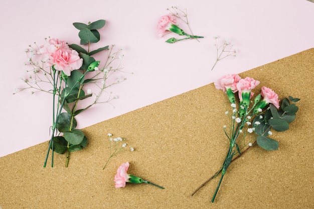 Fresh gypsophila and carnation flowers on dual pink and cardboard background