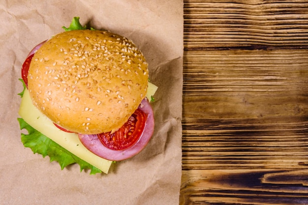 Fresh hamburger on brown paper on rustic wooden table