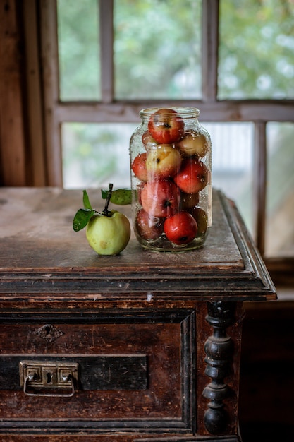 Fresh harvest of ripe and healthy farm apples in a glass jar, in a basket.