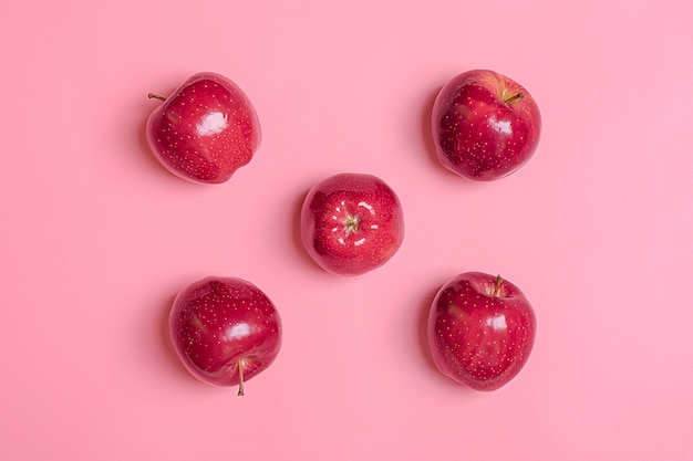 Свежесобранное красное яблоко лежит на трендовом розовом тысячелетнем фоне