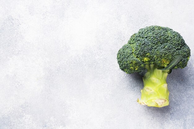 Photo fresh head of broccoli on grey concrete table. copy space.