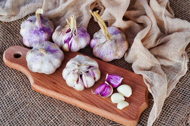 Fresh head of garlic and cloves on a wooden board in a rustic style eco products concept