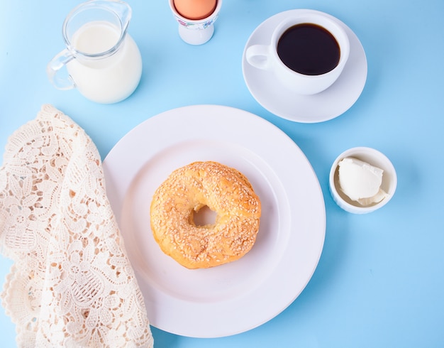 Fresh healthy bagel on a white plate with cup of coffee