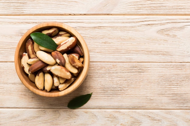 Fresh healthy Brazil nuts in bowl on colored table background Top view Healthy eating bertholletia concept Super foods