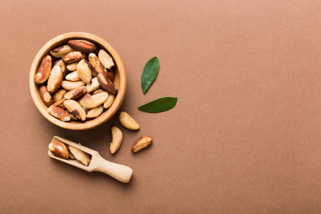 Fresh healthy Brazil nuts in bowl on colored table background Top view Healthy eating bertholletia concept Super foods