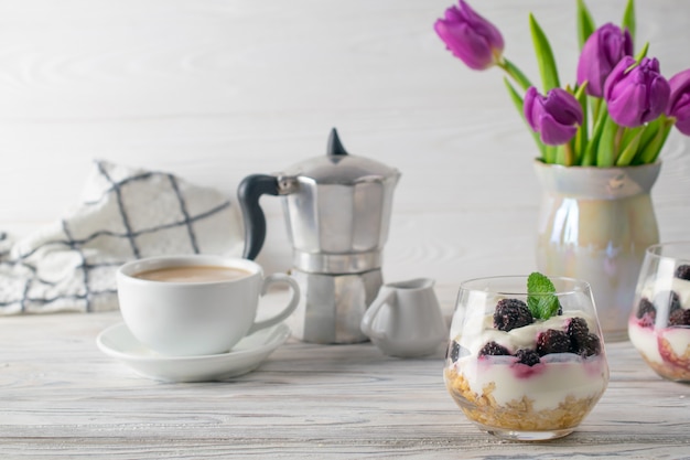 Fresh and healthy breakfast with granola, yogurt, coffee and purple tulips bouquet