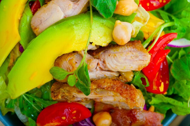 Fresh and healthy chicken avocado salad over rustic wood table