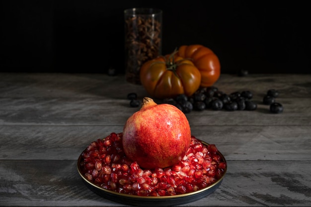 Fresh and healthy dessert of red and refreshing pomegranate grains on a wooden table