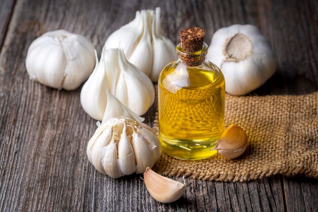 Fresh healthy garlic oil on the wooden background.