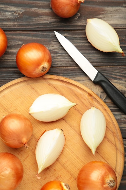 Fresh healthy onions and sliced onion on cutting board on brown background Vertical photo Top view