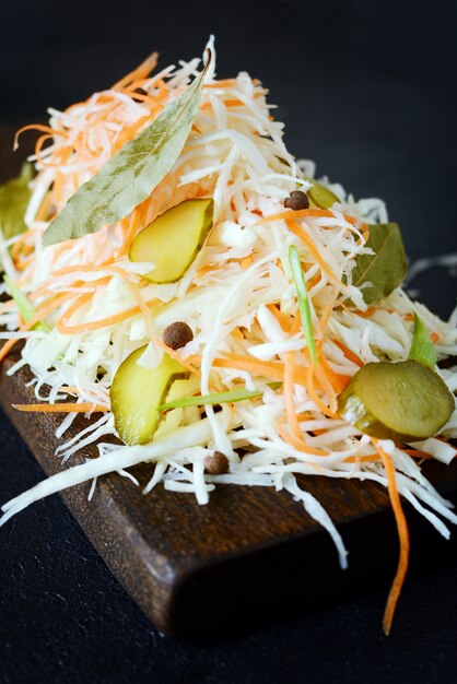 Fresh healthy salad - cabbage, carrot,pickle. Coleslaw on a wooden board on a light wall. Vegetables for ferment, for long fermentation.Assortment of fresh vegetables. Healthy food conception.