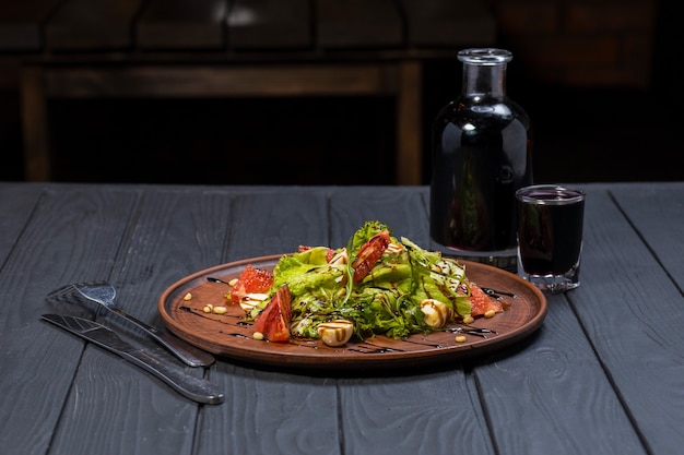 Fresh healthy salad with wine on black wooden table