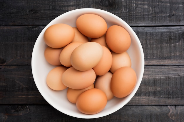 Fresh hen egg in white bowl on Black color wood table