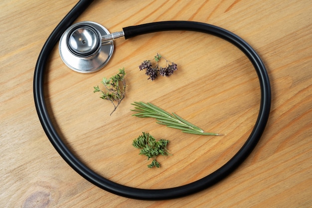 Fresh herb and stethoscope on wooden table. Alternative medicine concept.