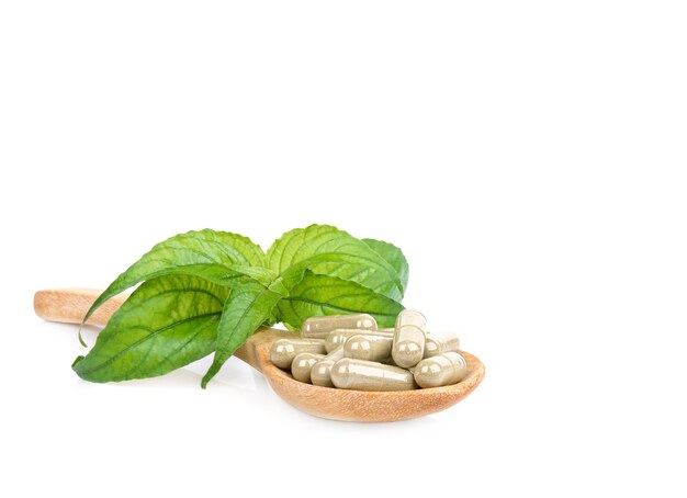 Fresh herbs and capsules in a wooden spoon Isolated