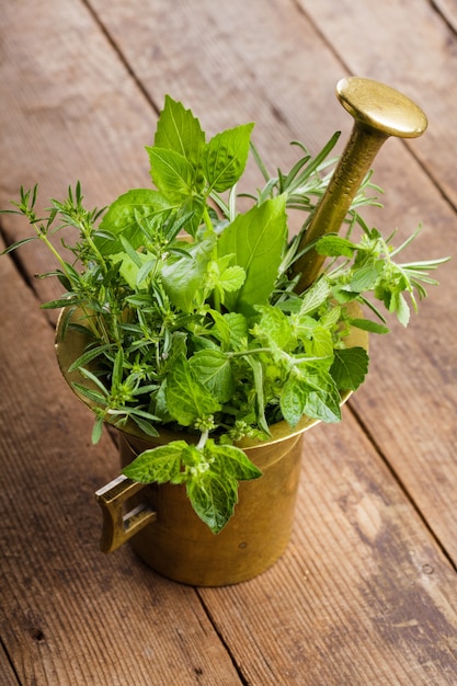 Fresh herbs in the copper mortar on the table