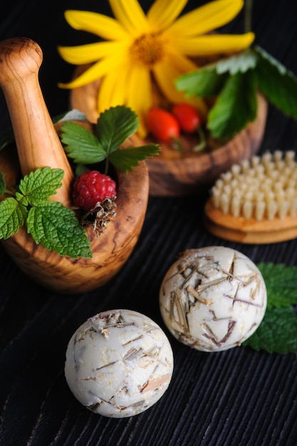 Fresh herbs in wooden mortar and bath bombs