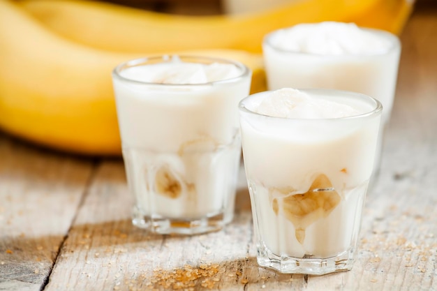 Fresh homemade banana yogurt in glass on old wooden table selective focus