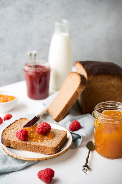 Fresh homemade bread with jam and milk, homemade simple food, light background