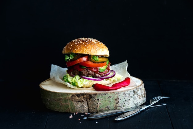 Fresh homemade burger on wooden serving board with spicy tomato sauce, sea salt and herbs