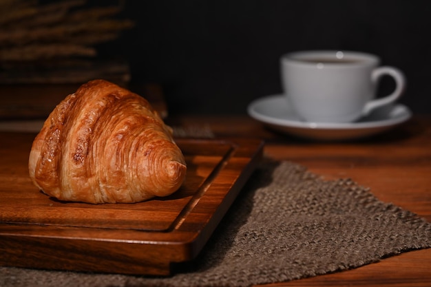 Fresh homemade butter croissant and coffee cup on wooden table Breakfast bread bakery products cafe concept