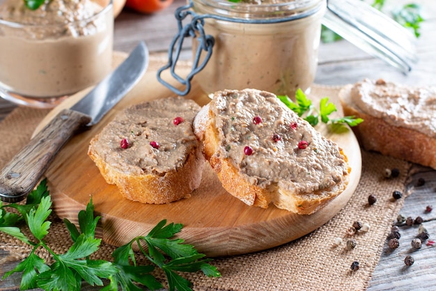 Fresh homemade chicken liver pate on bread on rustic wooden background