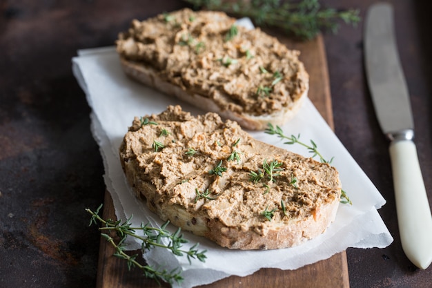 Свежий домашний паштет из куриной печени. Паштет из куриной печени на хлебе и в банке на темном фоне