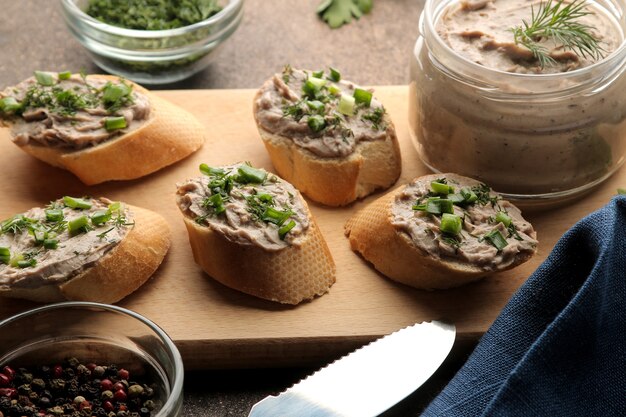 Fresh homemade chicken liver pate with greens on bread on a dark background. A sandwich.