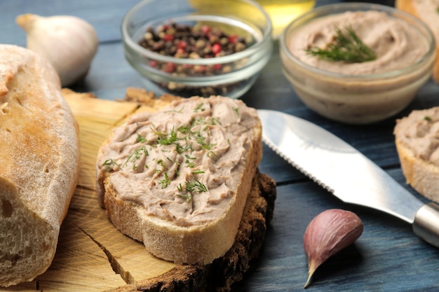 Fresh homemade chicken liver pate with herbs on bread on a blue wooden table. A sandwich. close-up