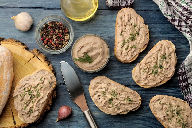 Свежий домашний паштет из куриной печени с зеленью на хлебе на синем деревянном столе. Бутерброд. вид сверху