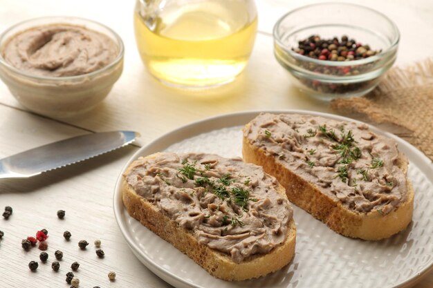 Fresh homemade chicken liver pate with herbs for bread on a white wooden table. A sandwich.