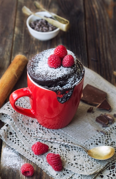 Photo fresh homemade chocolate cake in mug on rustic wooden background. cooked in microwave.