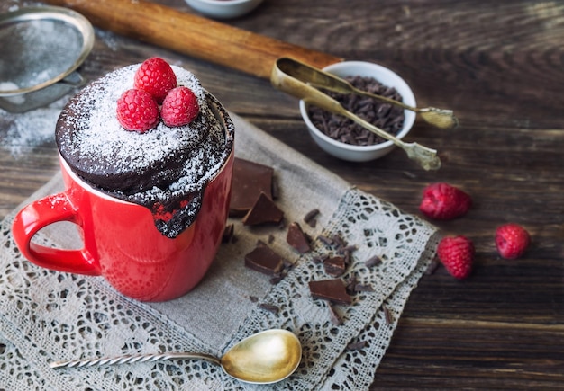 Foto torta al cioccolato fresca fatta in casa in tazza su fondo di legno rustico cotta nel microonde