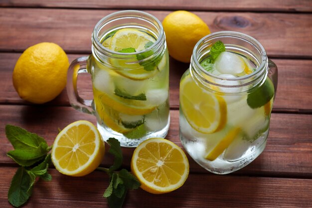 Fresh homemade citrus lemonade with lemons mint and ice on a wooden table Summer refreshing drinks