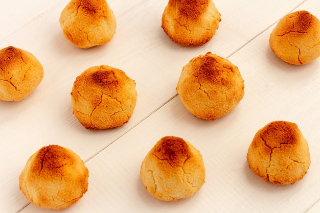 Fresh homemade cookies laid out in rows on white wooden table