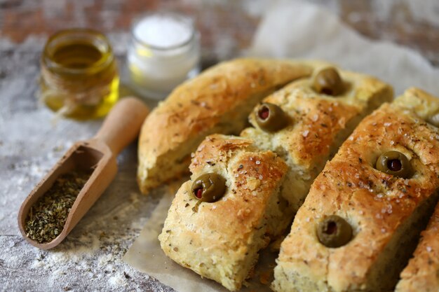 Fresh homemade focaccia with italian herbs. Cooking at home. Traditional italian bread with olives.