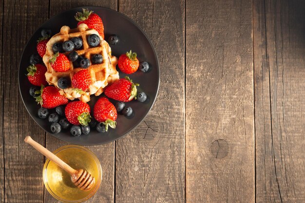 Fresh homemade food of berry Belgian waffles with honey chocolate strawberry blueberry