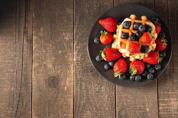 Fresh homemade food of berry Belgian waffles with honey strawberry blueberry and syrup