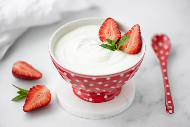 Foto yogurt greco fresco fatto in casa con fragole fresche in una ciotola rossa