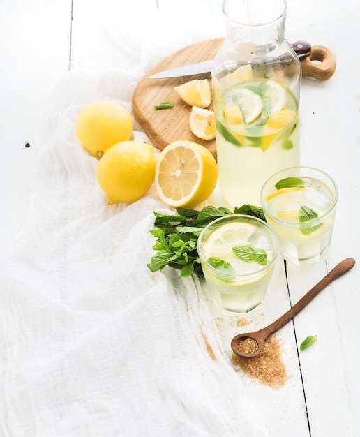 Limonata fresca fatta in casa con limoni e menta su fondo di legno bianco