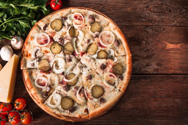 Foto pizza fresca fatta in casa servita su un tavolo di legno con vista dall'alto degli ingredienti, con copyspace per il testo