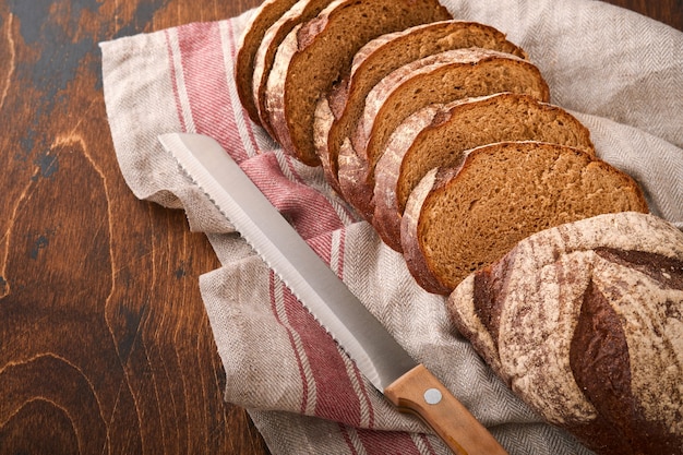 Fresh homemade rye bread. Traditional spelled sourdough bread cut into slices on a rustic wooden background. Concept of traditional leavened bread baking methods. Selective focus.