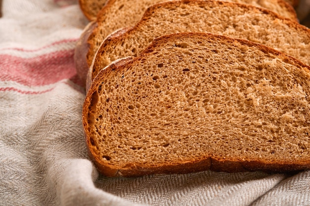 Fresh homemade rye bread. Traditional spelled sourdough bread cut into slices on a rustic wooden background. Concept of traditional leavened bread baking methods. Selective focus.