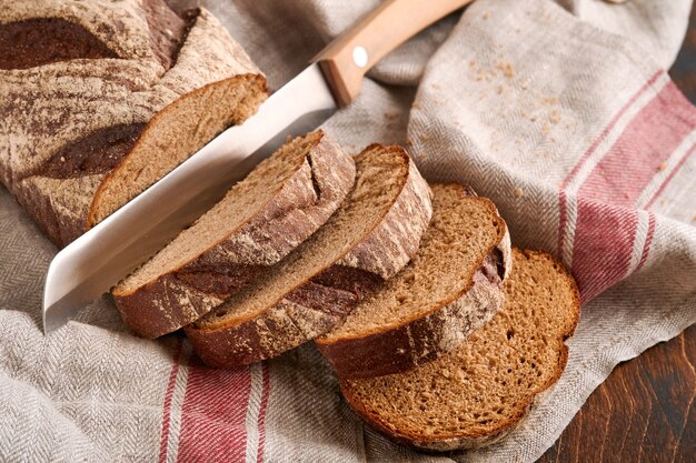 Fresh homemade rye bread. Traditional spelled sourdough bread cut into slices on a rustic wooden background. Concept of traditional leavened bread baking methods. Selective focus.