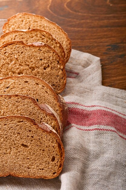 焼きたての自家製ライ麦パン。素朴な木製の背景にスライスにカットされた伝統的なスペルト小麦のサワードウパン。伝統的な発酵パンの焼き方の概念。セレクティブフォーカス。