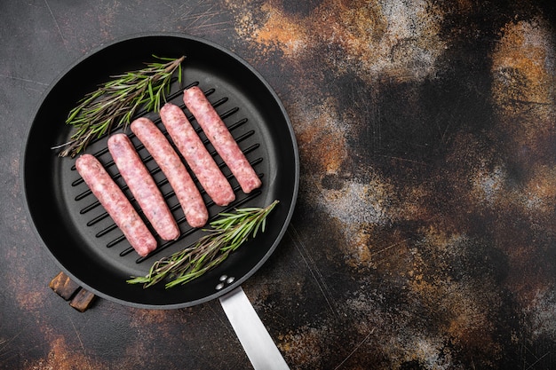 Fresh homemade sausages set, on frying cast iron pan, on old dark rustic table background, top view flat lay, with copy space for text