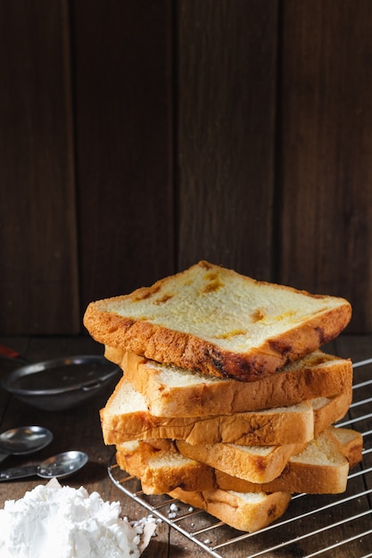 Fresh homemade sliced bread stacked on wood table dark texture background