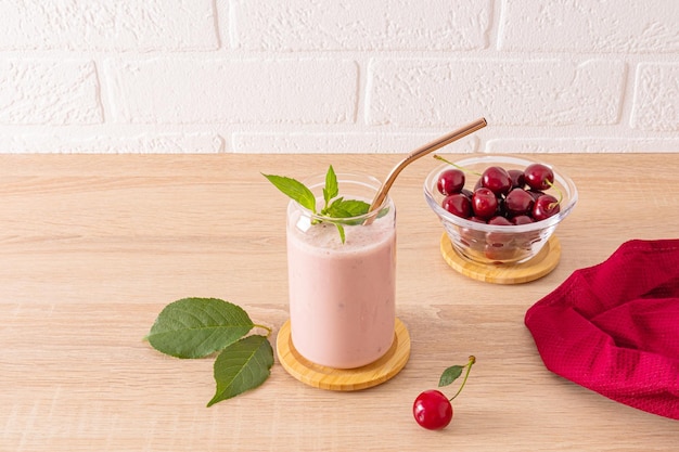 Fresh homemade smoothie made from ripe cherries in a stylish glass on a wooden countertop Healthy organic beverage