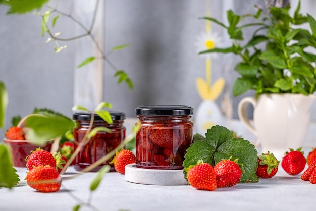 Foto marmellata di fragole fresca fatta in casa in un barattolo di vetro su uno sfondo chiaro