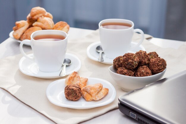 Biscotti di zucchero fatti in casa freschi con tè, laptop sul tavolo con luci del sole. lavora dal concetto di casa.